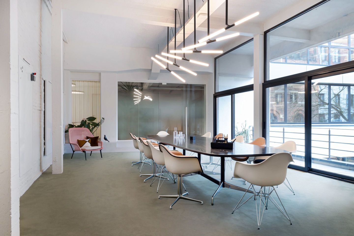 Heller Konferenzraum mit Eames Plastic Arm Chairs und Sitzpolster von Vitra am Tisch.
