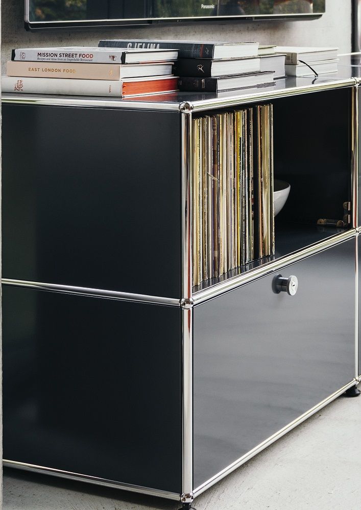 Nahaufnahme eines schwarzen USM Haller Sideboards mit einer Klappe und einem offenen Fach.