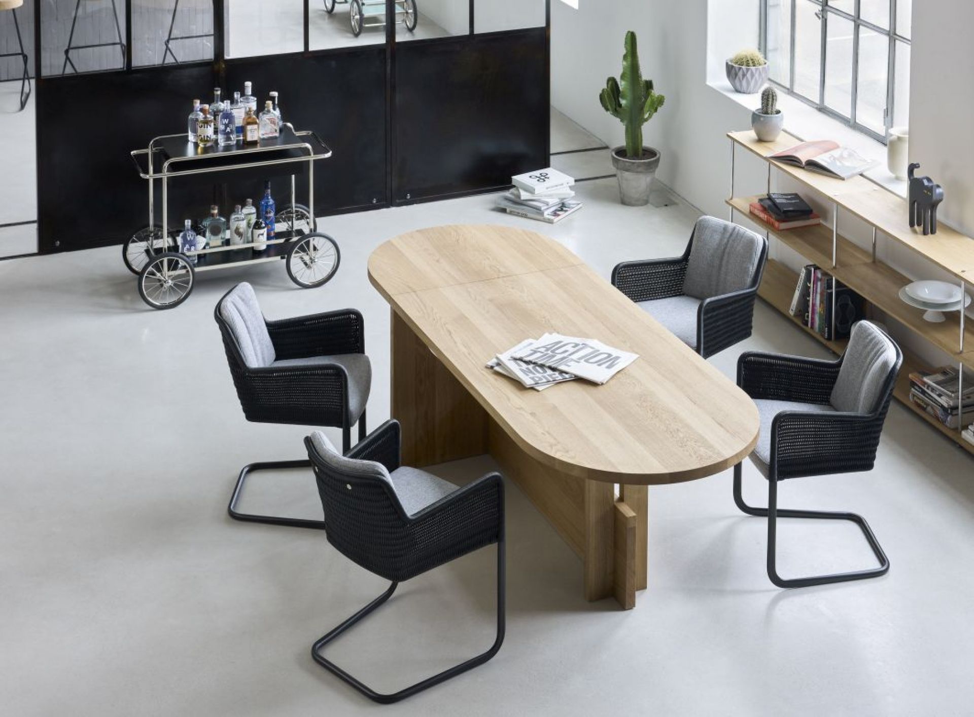 Heller Raum mit Esstisch, Stühlen und Tecta M4RS Barwagen im Hintergrund.