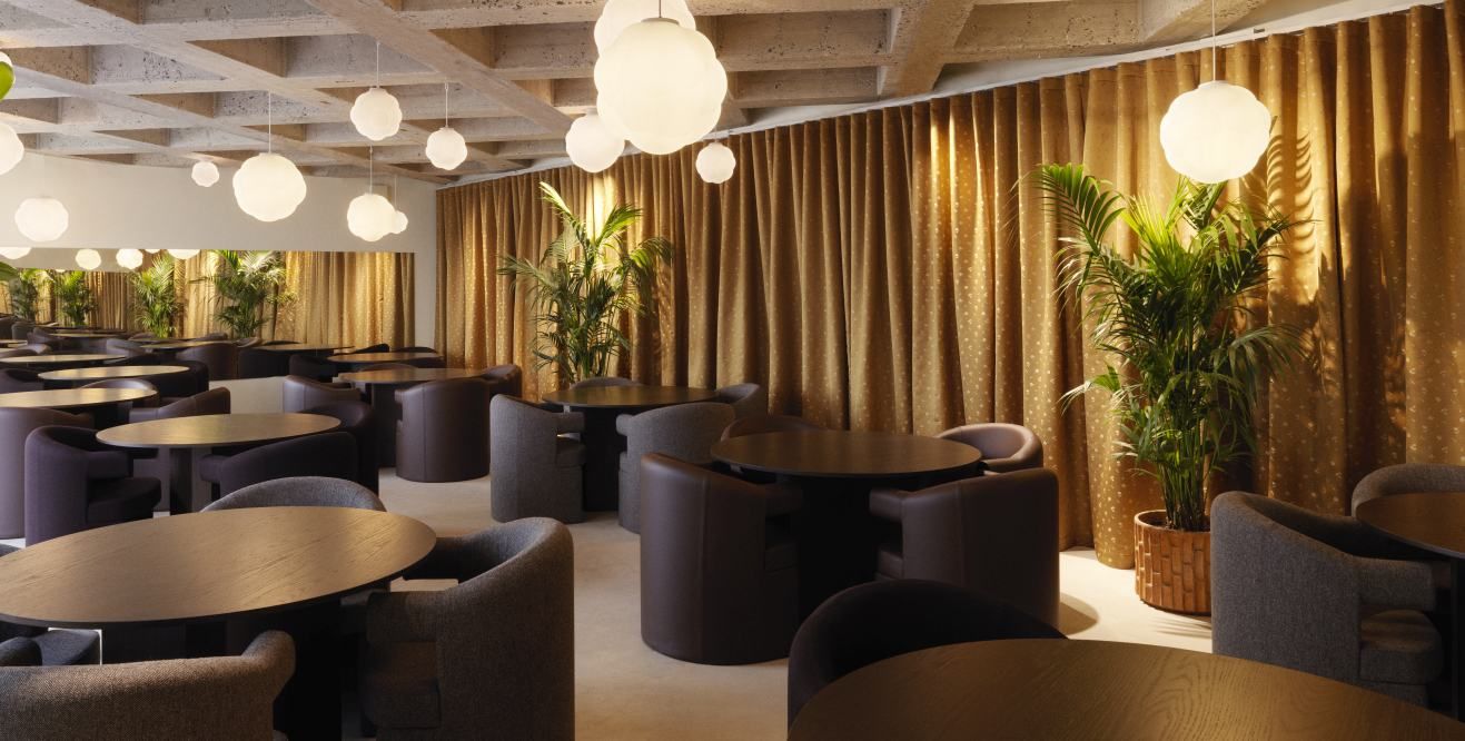 Innenraum mit Bubba Pendelleuchten von Normann Copenhagen, runden Tischen und Sesseln.