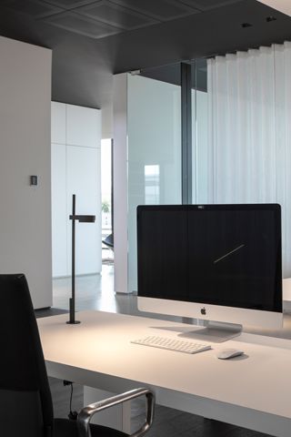 Kido Desk Tischleuchte von Belux, schwarze Ausführung mit fester Befestigung auf einem Schreibtisch.