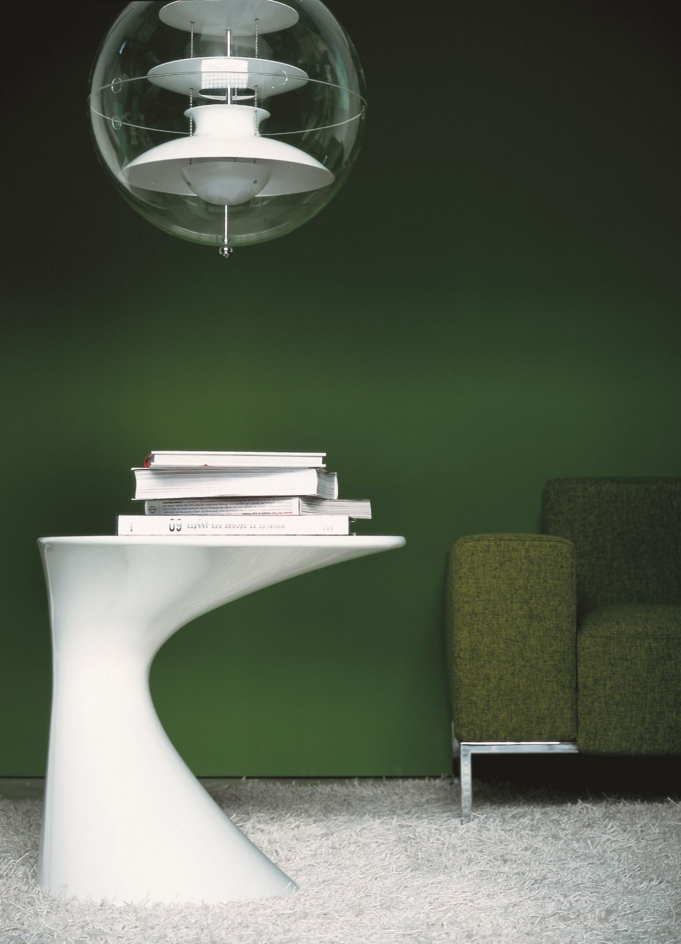 Weißer Zanotta Tod Couchtisch mit Büchern, Stehlampe und grünem Sofa auf einem weißen Teppich.