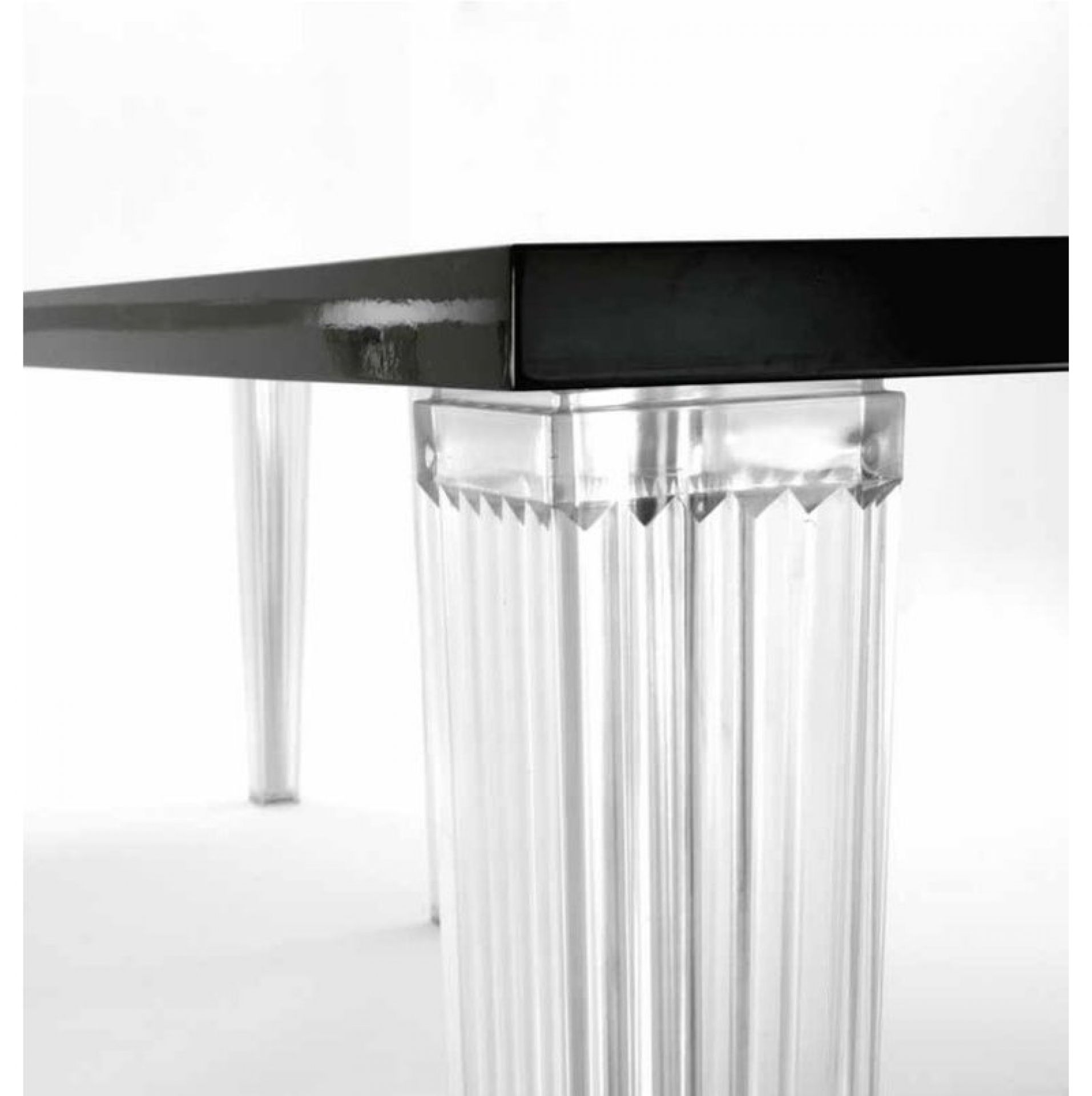 Detailaufnahme vom Kartell Top Top Glastisch mit schwarzer Tischplatte und transparenten, geriffelten Beinen.