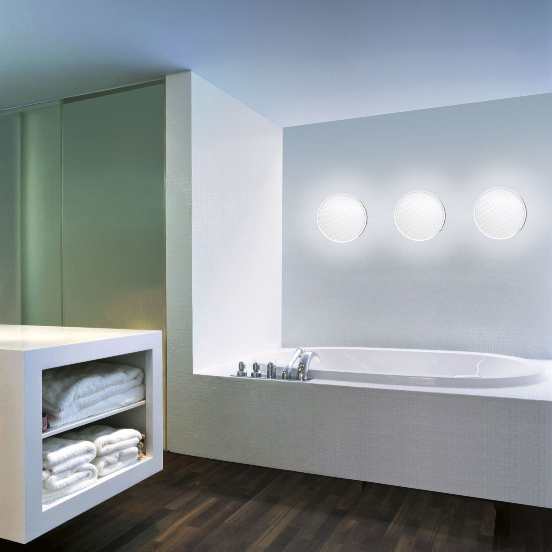 Badezimmer mit Badewanne und drei runden O-lite Wandleuchten von Belux an der Wand.