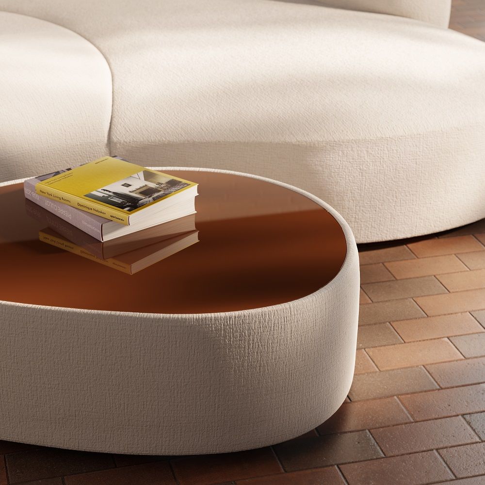 Detailaufnahme: Runder Siwa Couchtisch mit brauner Glasplatte und beigem Stoffbezug, Bücher darauf.