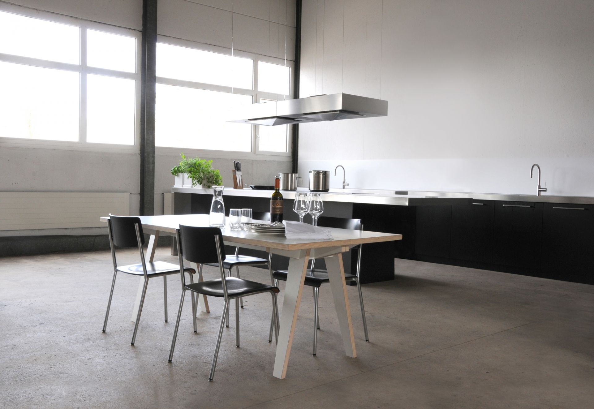 Moderner Tojo Tisch aus Holz mit Stühlen in minimalistischer Küche, gedeckt mit Geschirr.