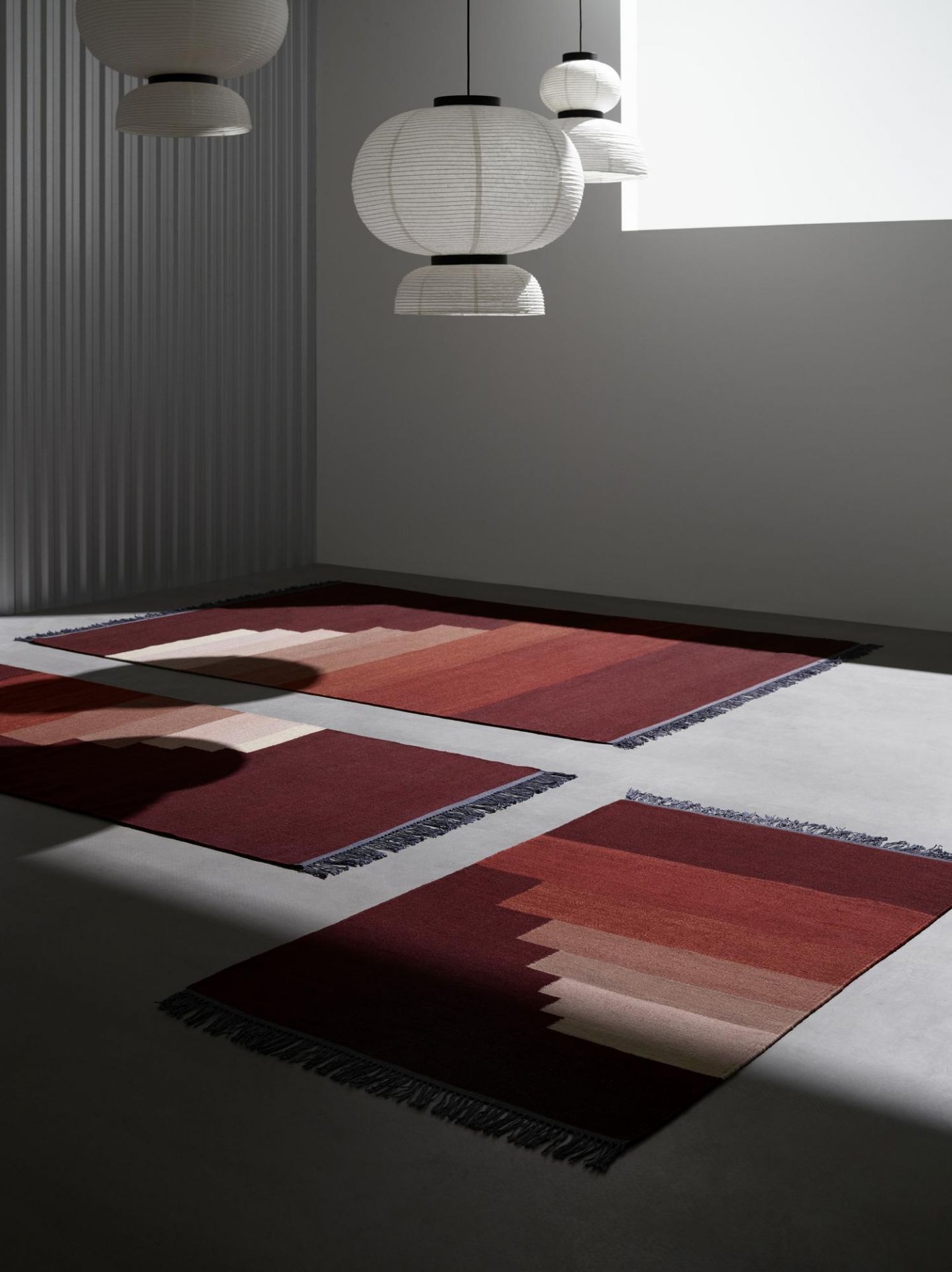 Ansicht von drei Teppichen mit der AndTradition Formakami JH5 Hängeleuchte im Hintergrund.