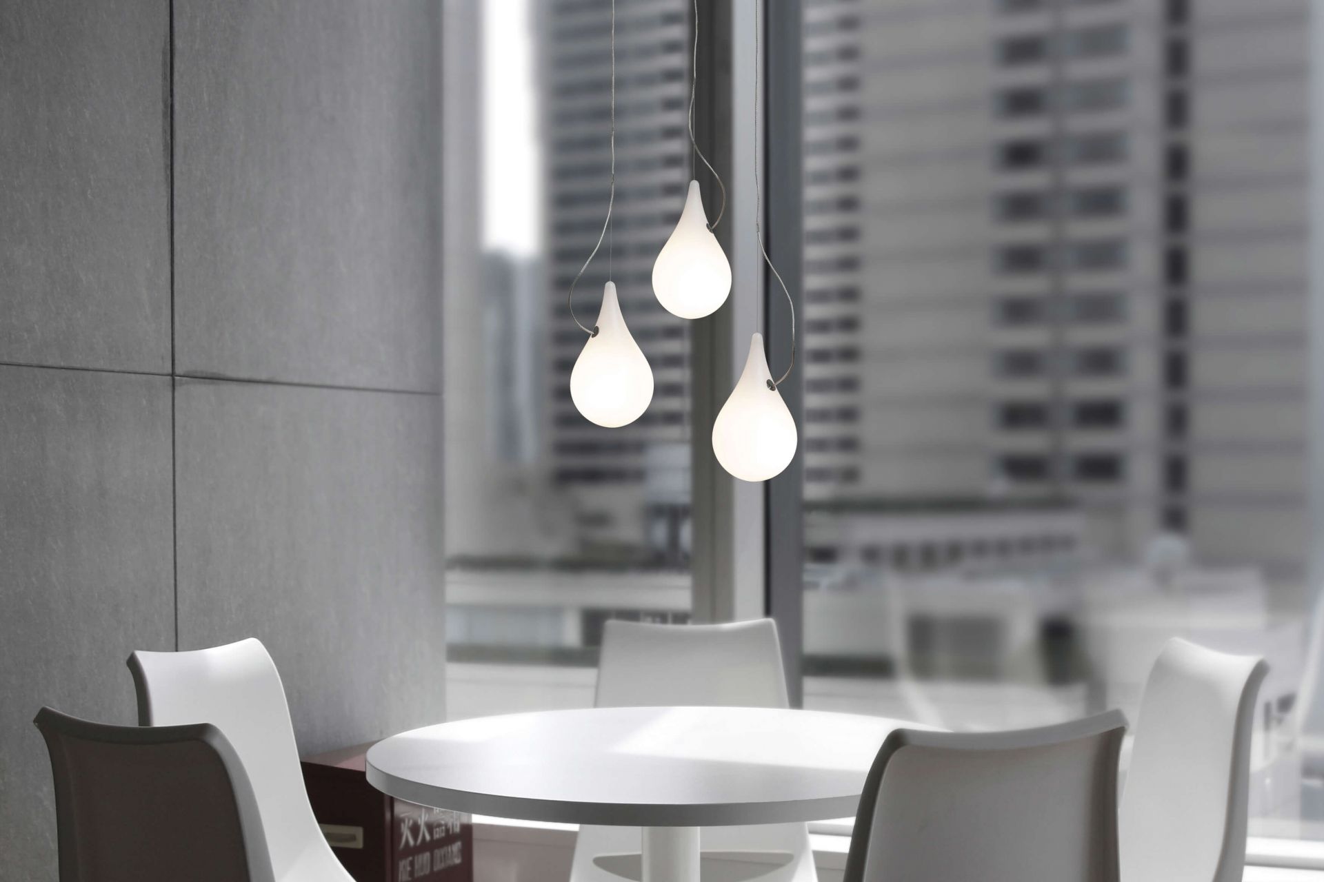 Liquid Light Pendelleuchte: Drei tropfenförmige Lampen über einem weißen Tisch, modernes Design.