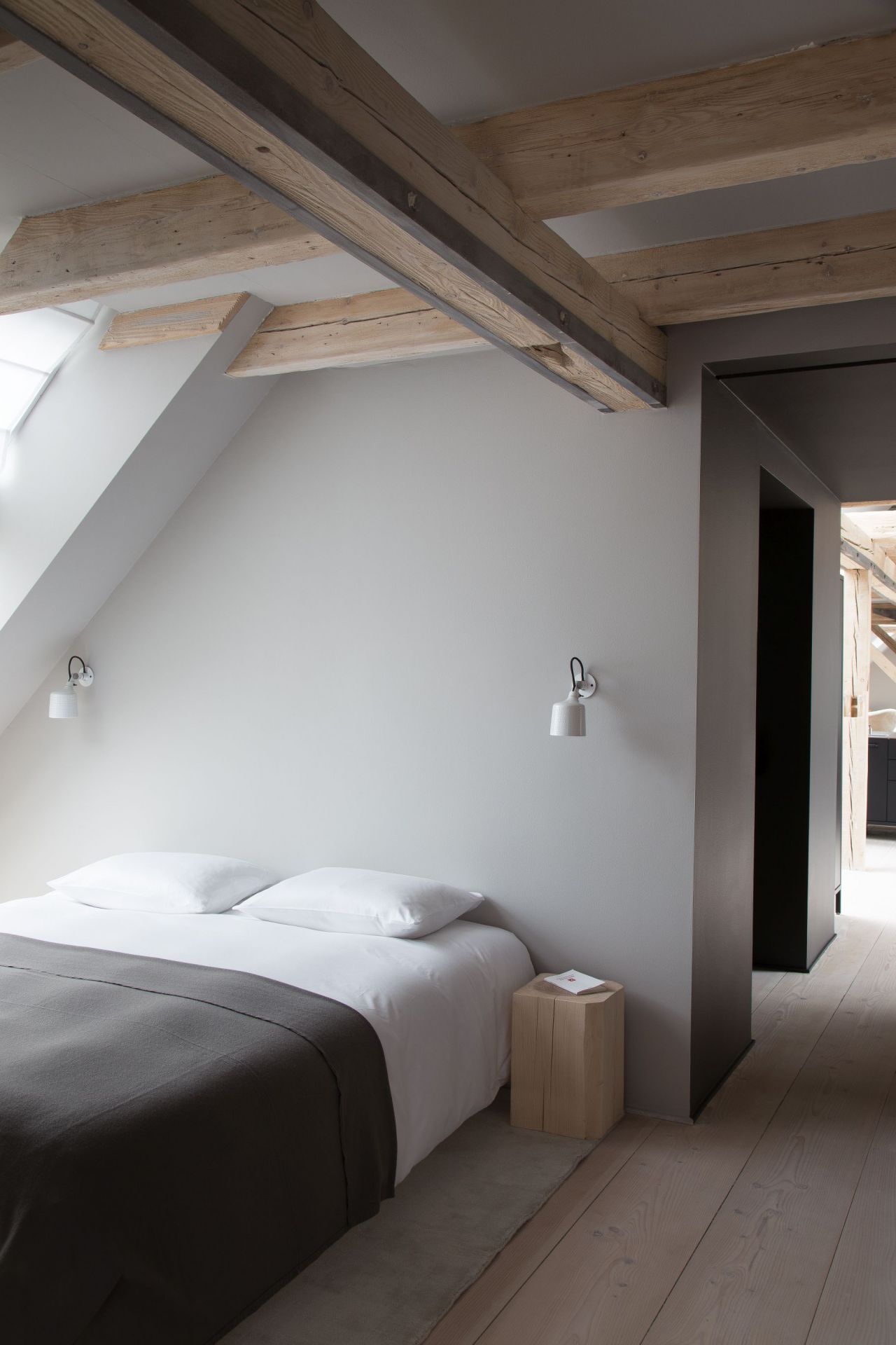 Schlafzimmer mit Bett und zwei weißen Vipp Wandspots als Beleuchtung an der Wand.