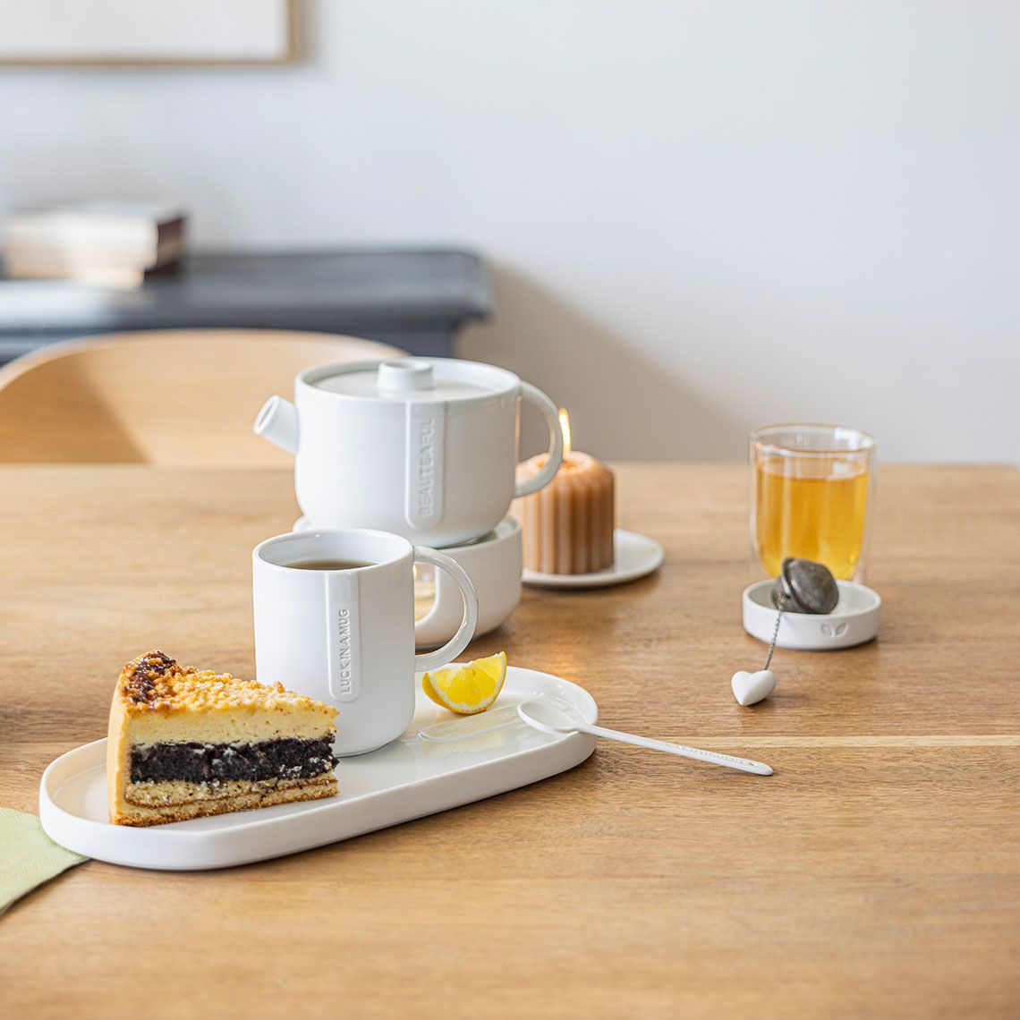 Cozy Time Stövchen und Teekanne von Räder mit Tee, Kuchen und Zitrone auf Tisch.