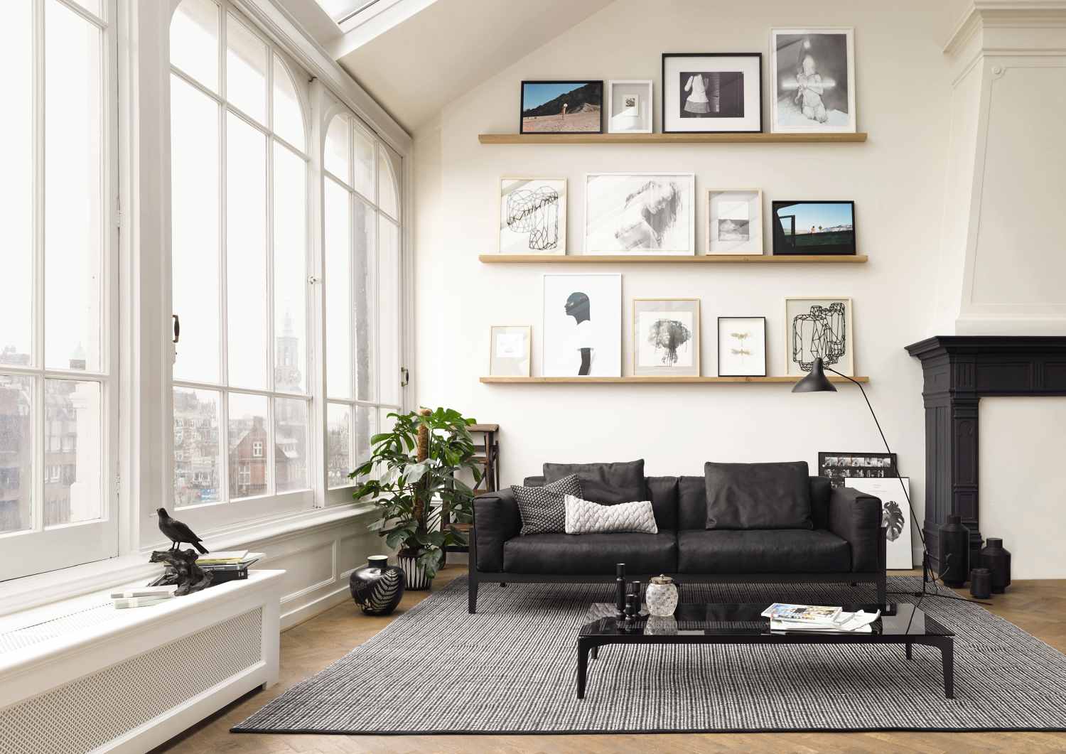 Wohnzimmer mit schwarzem Elm Sofa, Couchtisch und Teppich in modernem, hellem Ambiente.