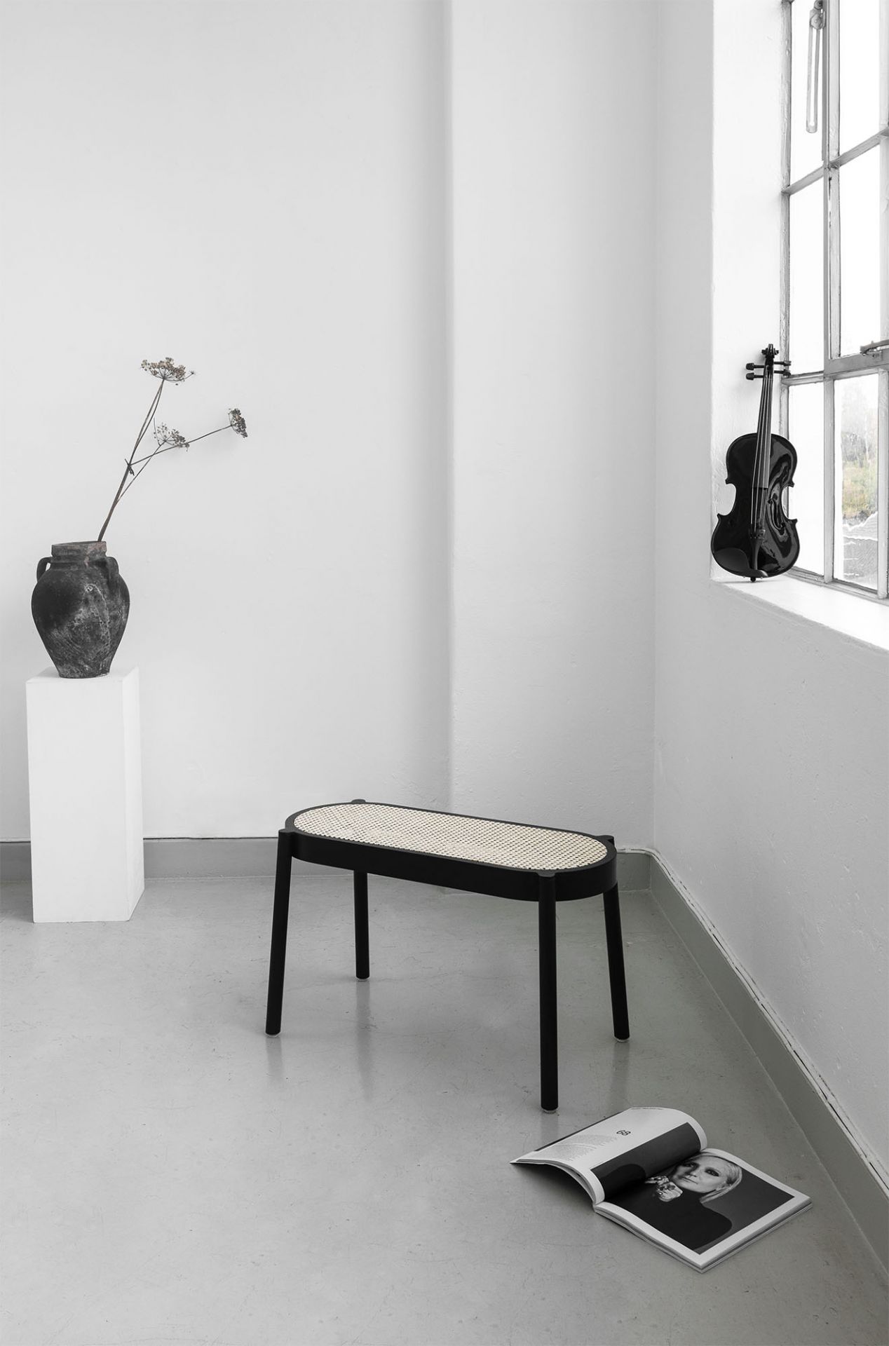 Pal Bank Northern: Schwarze Bank mit Rattan-Sitzfläche in minimalistischem Raum mit Dekoration.