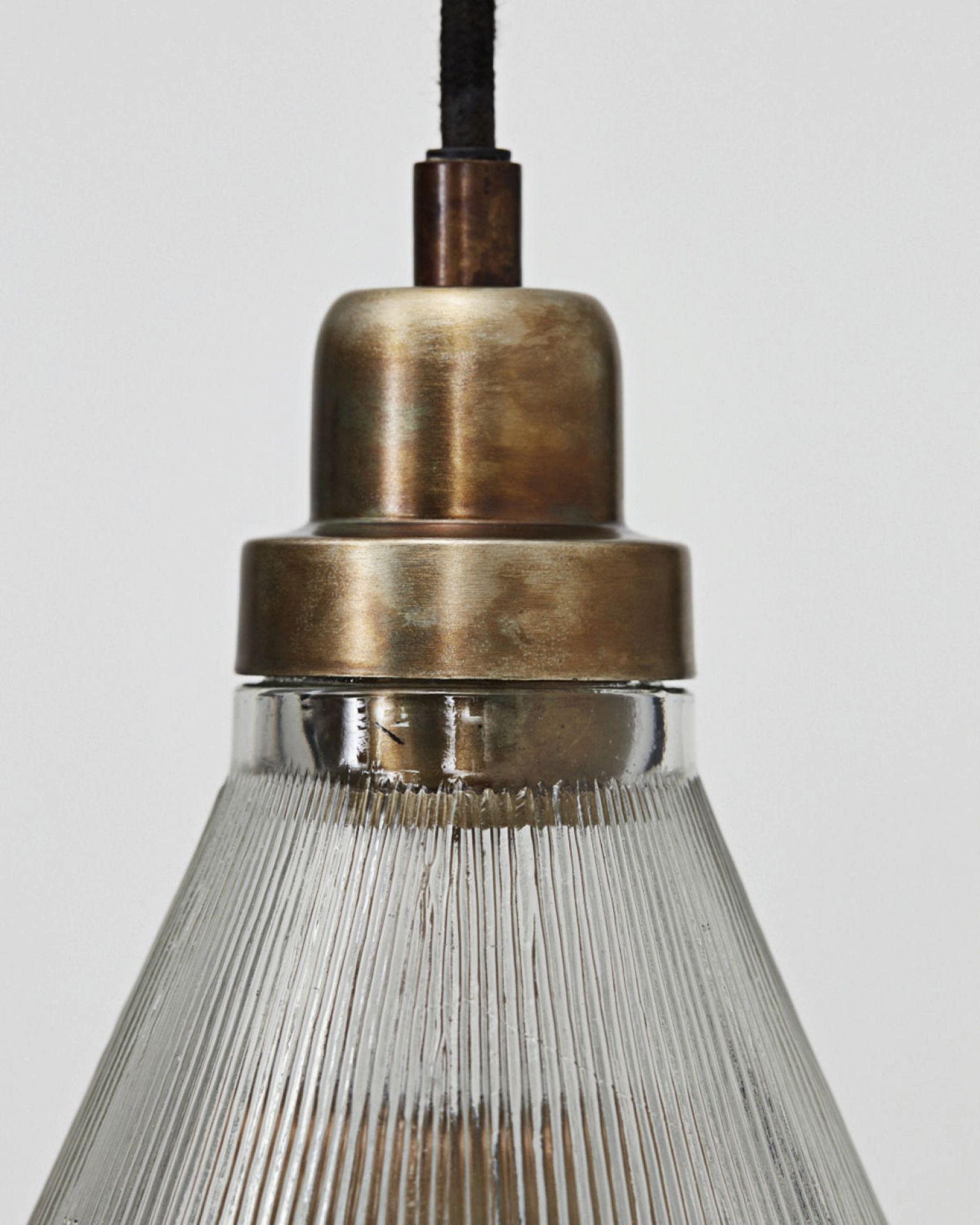 Detailaufnahme der Vira Pendelleuchte von House Doctor mit geriffeltem Glasschirm und Messingfassung.