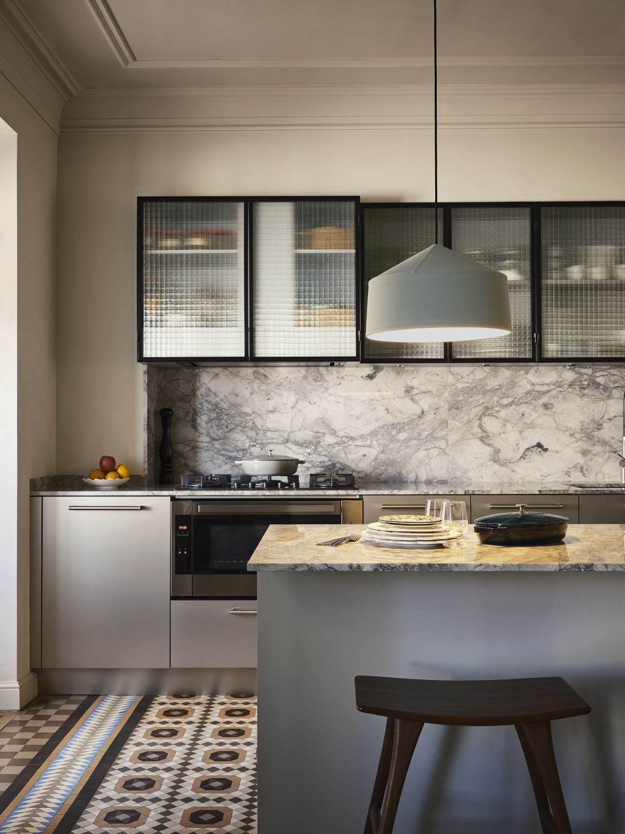 Graue Zenc Pendelleuchte von Marset hängt über einer modernen Küche mit Marmor und stilvollen Details.