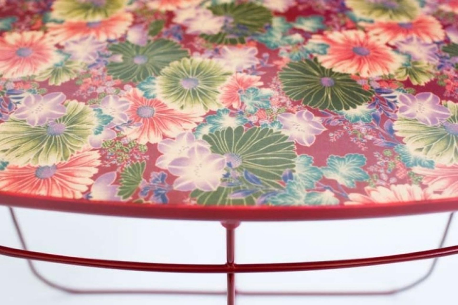 Detailaufnahme des Ukiyo Tischs von Moroso mit rotem Gestell und floralem Muster auf der Tischplatte.