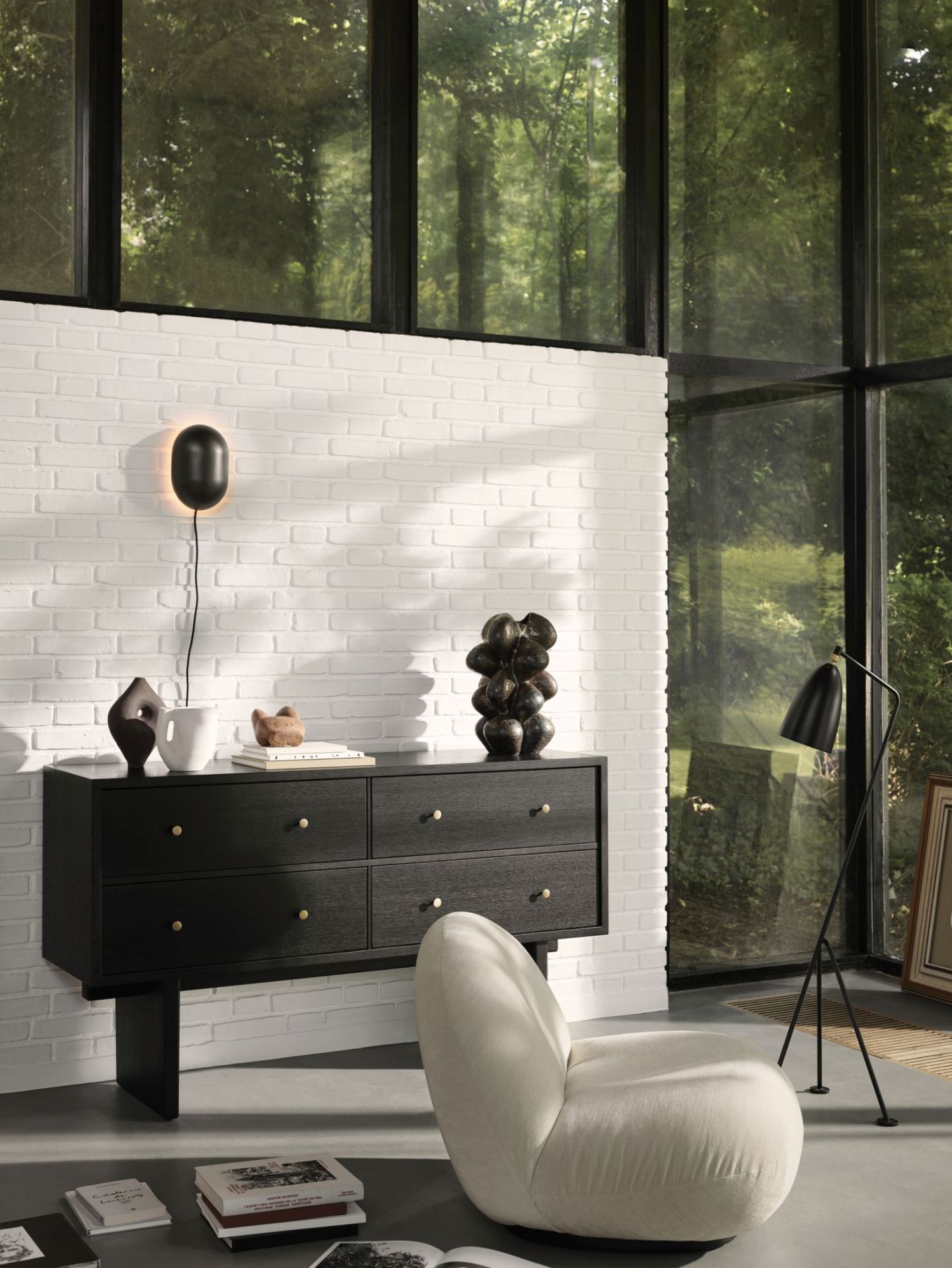 Pacha Lounge Chair Sessel in Weiß mit Drehfuß, vor schwarzer Kommode und großem Fenster.