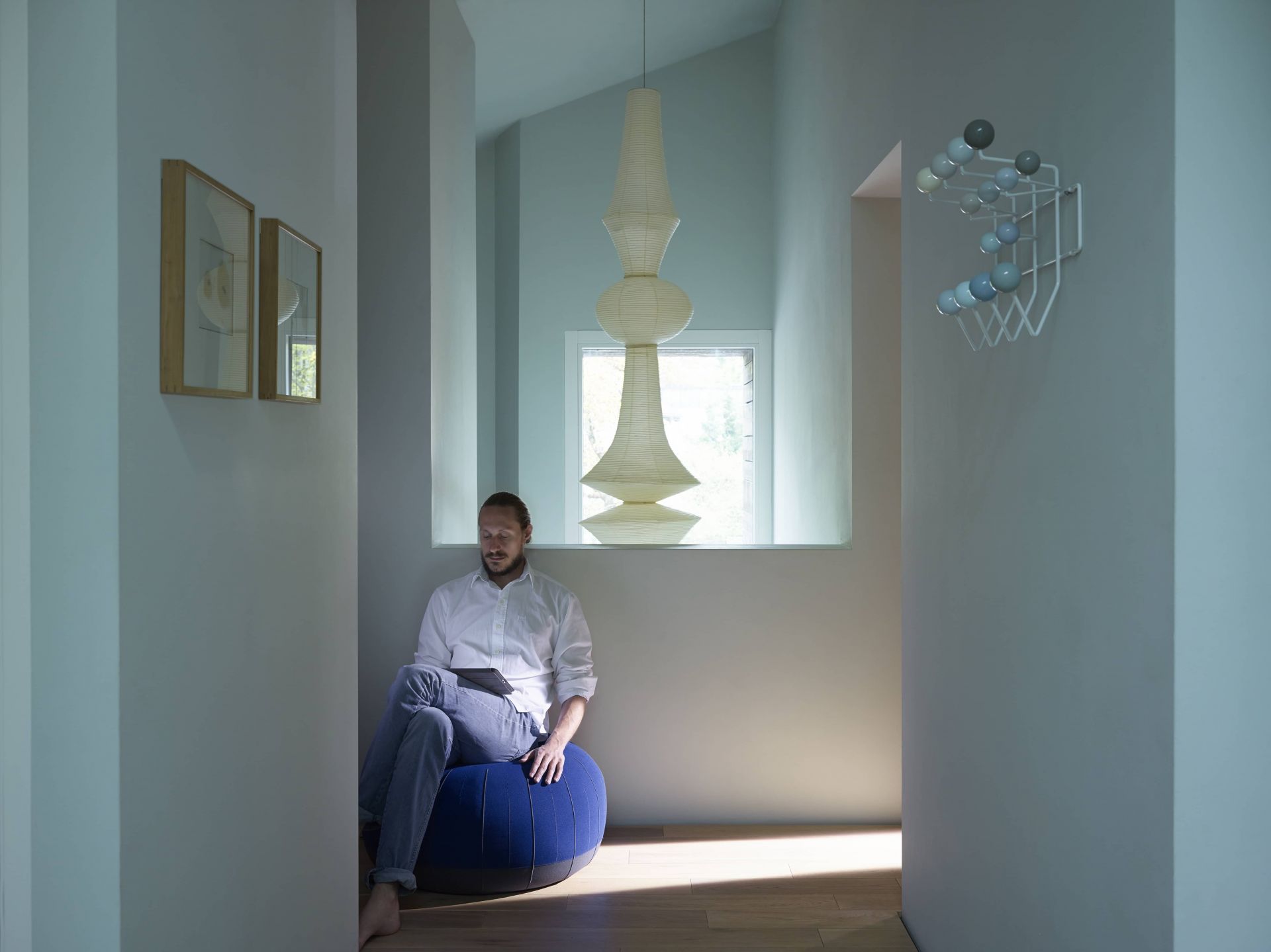 Mann sitzt unter einer Akari Hängeleuchte von Vitra, die den Raum mit sanftem Licht erfüllt.