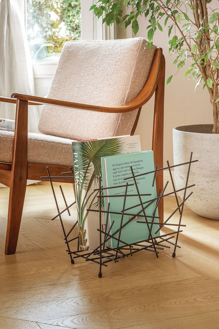 Schwarzer Alessi Zeitschriftenhalter "Blow Up" neben Sessel und Zimmerpflanze. Modernes Design für Zeitschriften und Bücher.