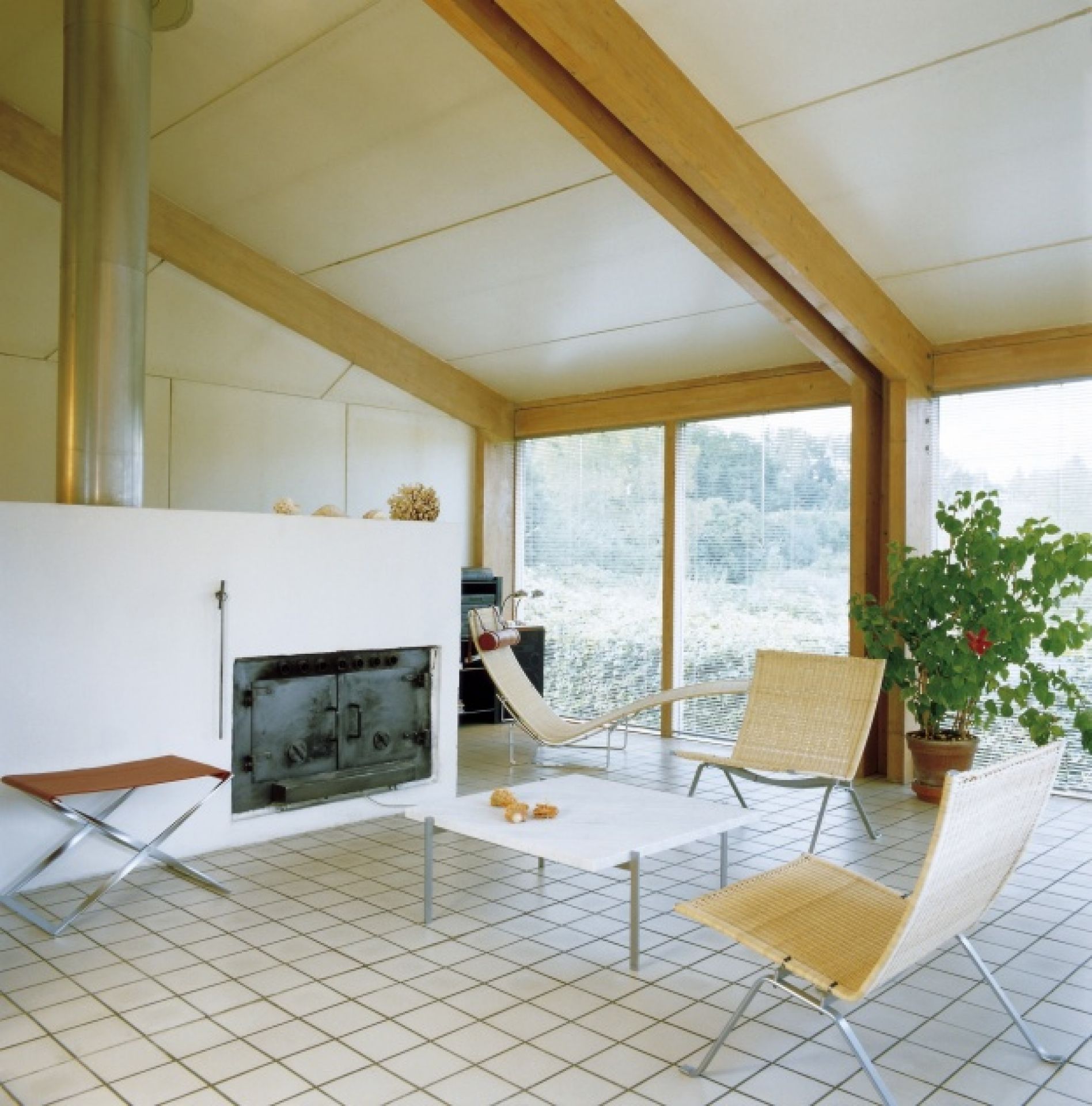 Helle Wohnzimmeransicht mit PK24 Liege von Fritz Hansen, Designklassiker und modernen Möbeln.