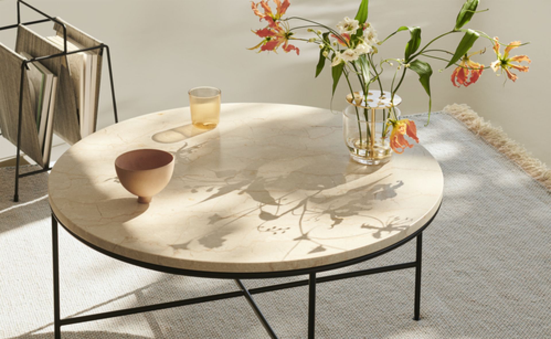 Runder Fritz Hansen Couchtisch mit Marmorplatte, Blumen, Schale und Glas im Wohnzimmer.