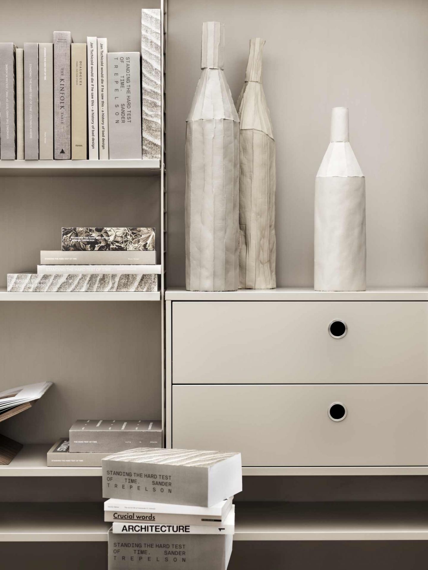 Detailaufnahme eines String Regalsystems mit Schubladen, Büchern und dekorativen Vasen.