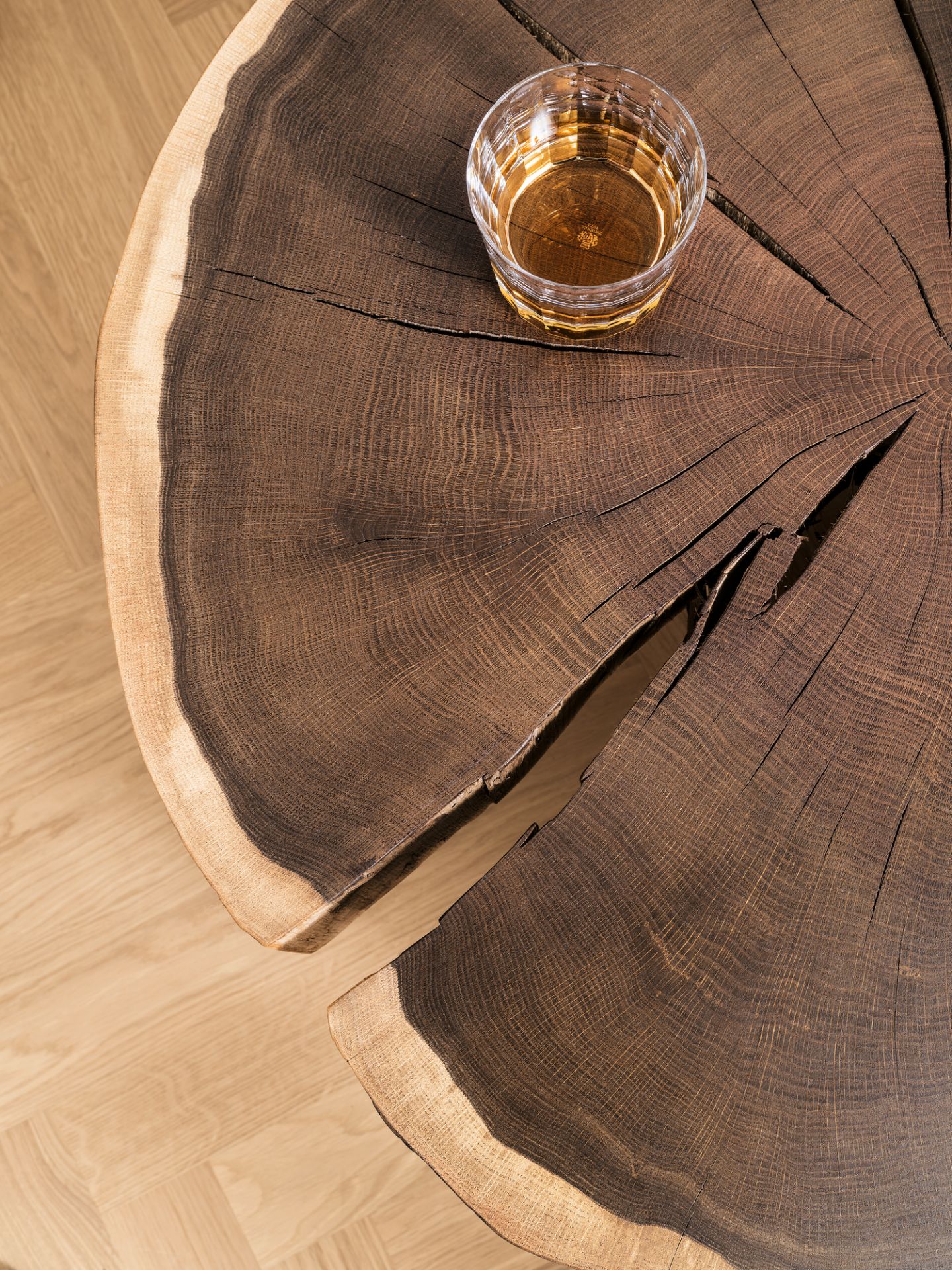 Nahaufnahme: Janua Stomp Beistelltisch H40 aus roher Eiche mit Getränk im Glas.