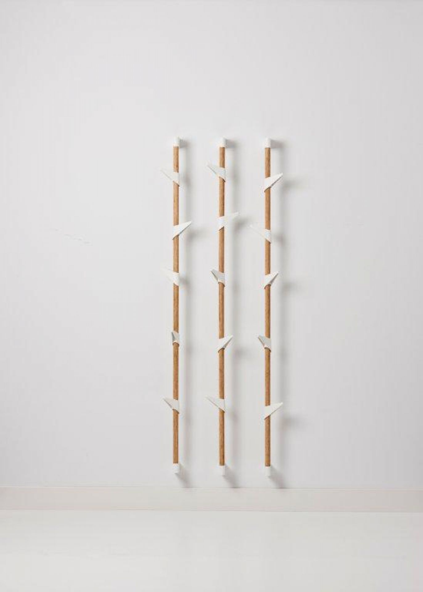 Cascando Bamboo Wandgarderobe mit drei Reihen aus Bambusstäben und weißen Haken.