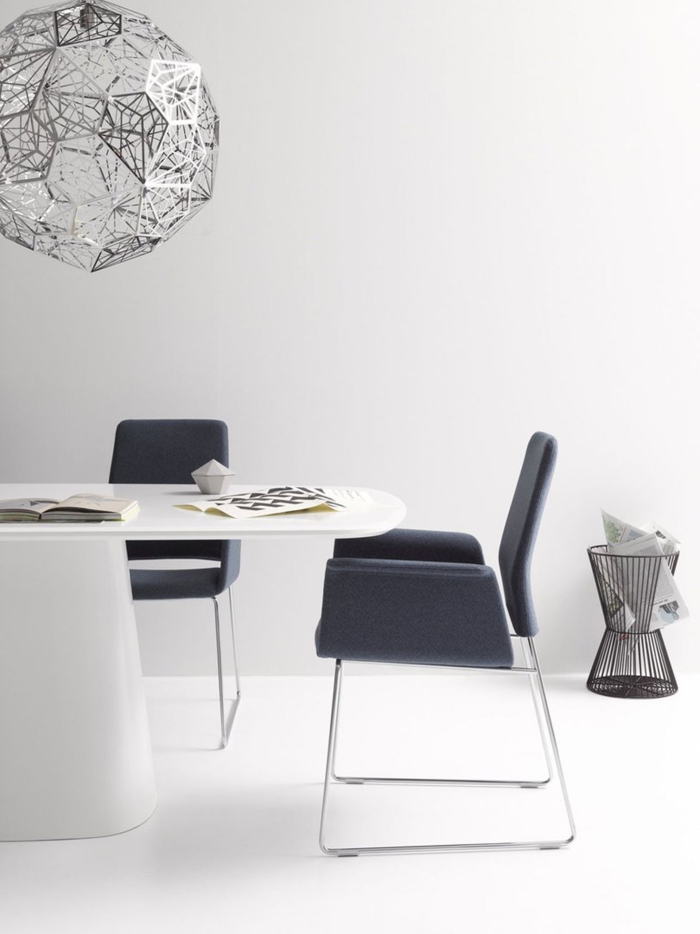 Conic Tisch mit Stühlen in modernem Büroambiente, minimalistisches Design mit weißem Tisch und blauen Stühlen.