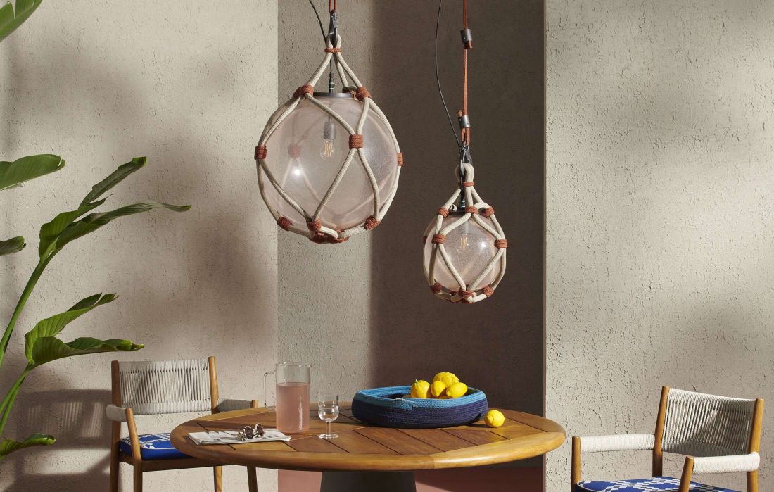 Zwei Bollicosa Nautilus Pendelleuchten von Cassina hängen über einem Outdoor-Esstisch. Dekorative Außenleuchten mit Seil.