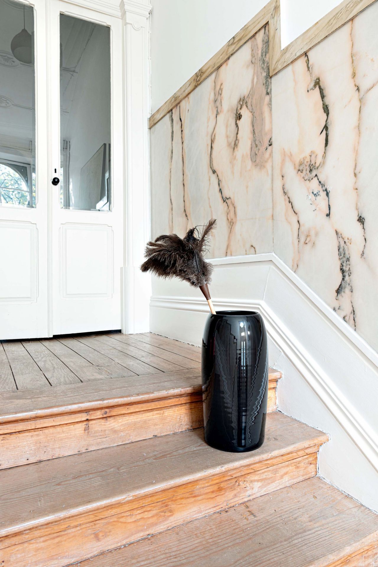 Carlo Schirmständer Charcoal Schönbuch: Schwarzer, zylindrischer Schirmständer mit Federbesen auf Holztreppe im Flur.