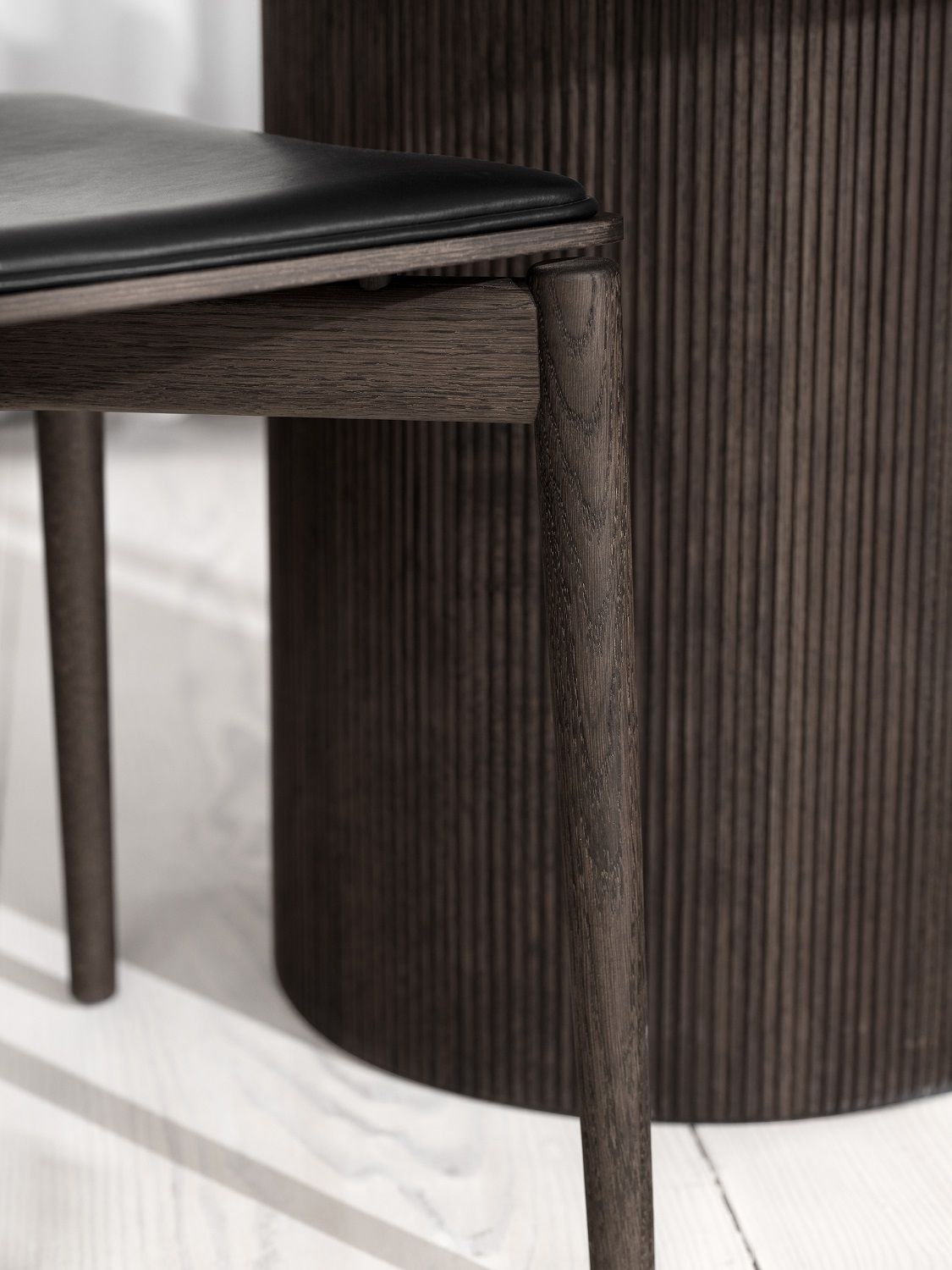 Detailaufnahme: Vipp Cabin Tisch, runde Tischplatte aus dunkler Eiche, geriffelte Oberfläche.