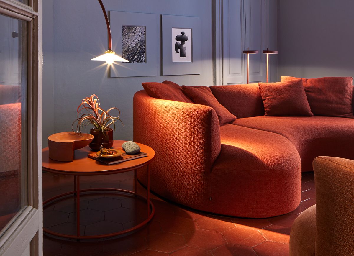 Gemütliches Wohnzimmer mit rotem Siwa Sofa und passendem Beistelltisch. Moderne Couch mit Liege.