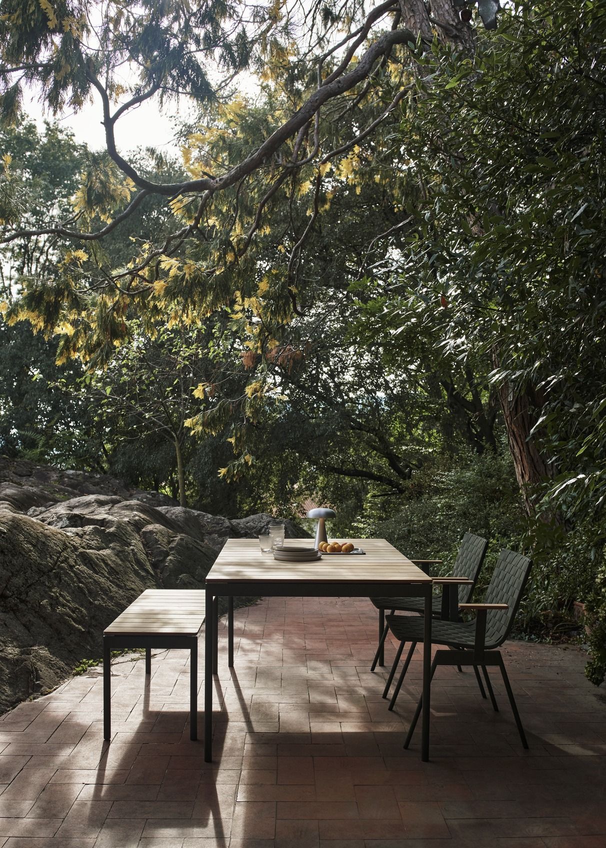 AndTradition Ville AV26 Outdoor Tisch mit Stühlen und Bank im Garten, gedeckt mit Geschirr.