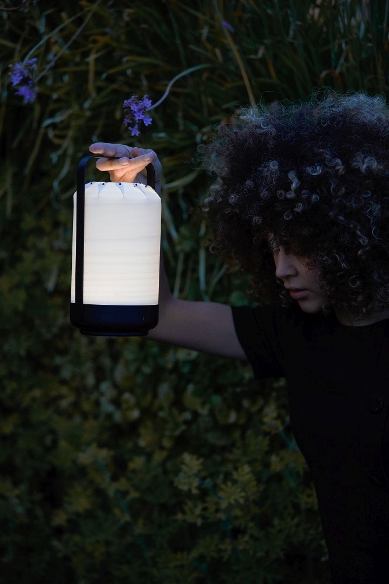 Frau hält Chou Mini LED Akkuleuchte von LZF Lamps im Garten. Tischleuchte mit USB.