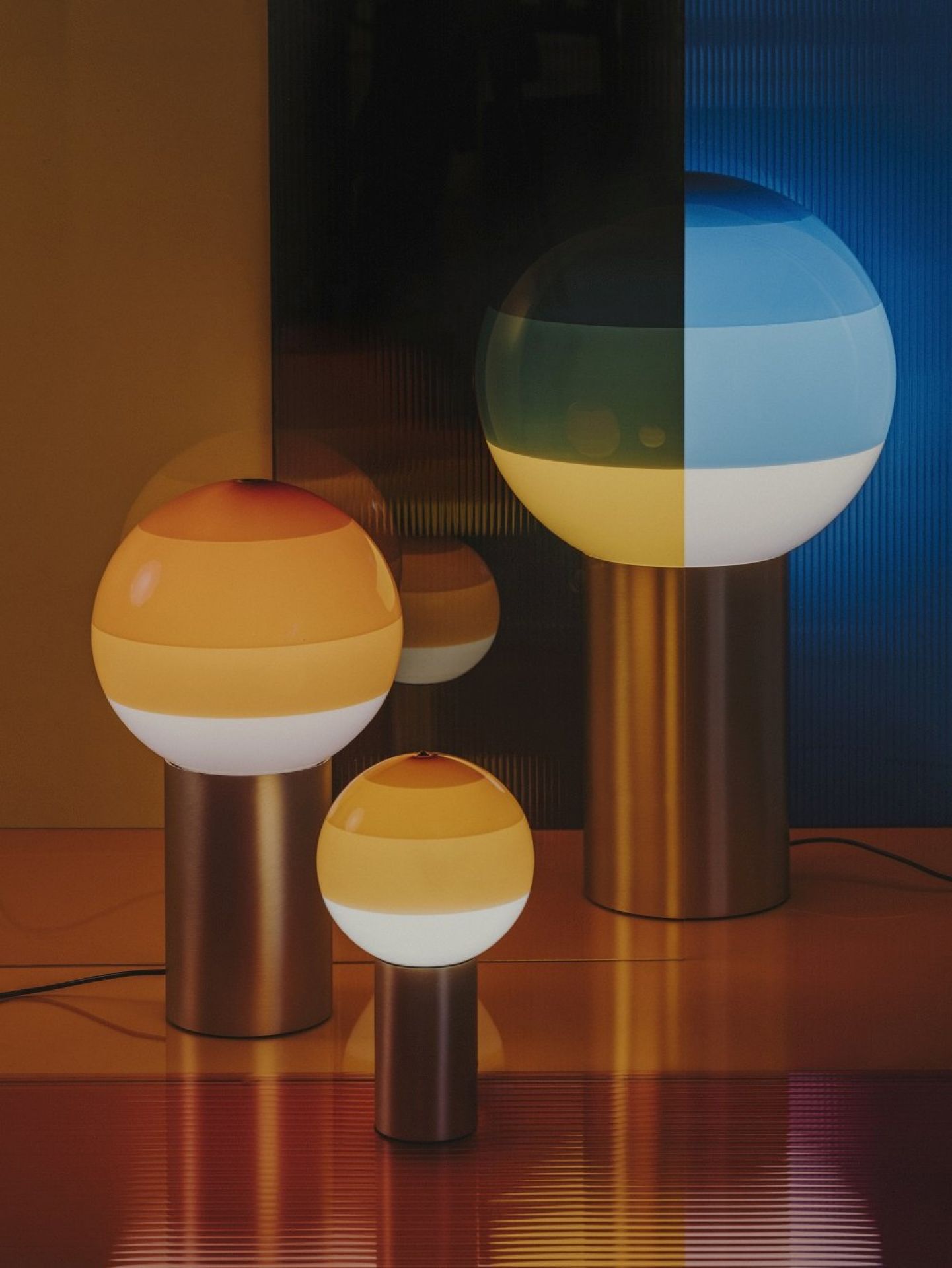 Nahaufnahme von drei Marset Dipping Light Tischleuchten in Bernstein und Messing.