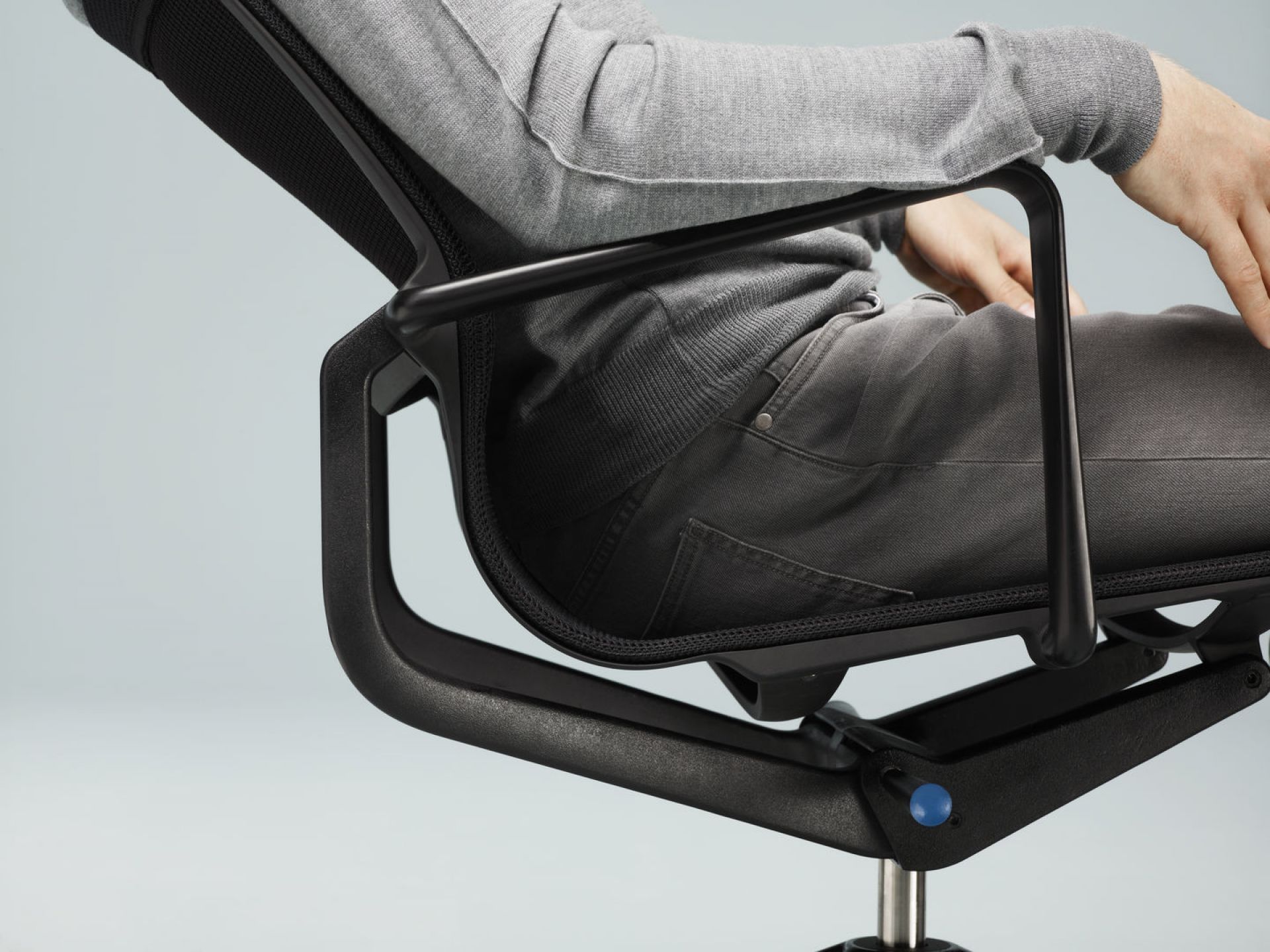 Detailaufnahme: Person sitzt im schwarzen Physix Bürostuhl von Vitra. Ergonomischer Drehstuhl für komfortables Sitzen.