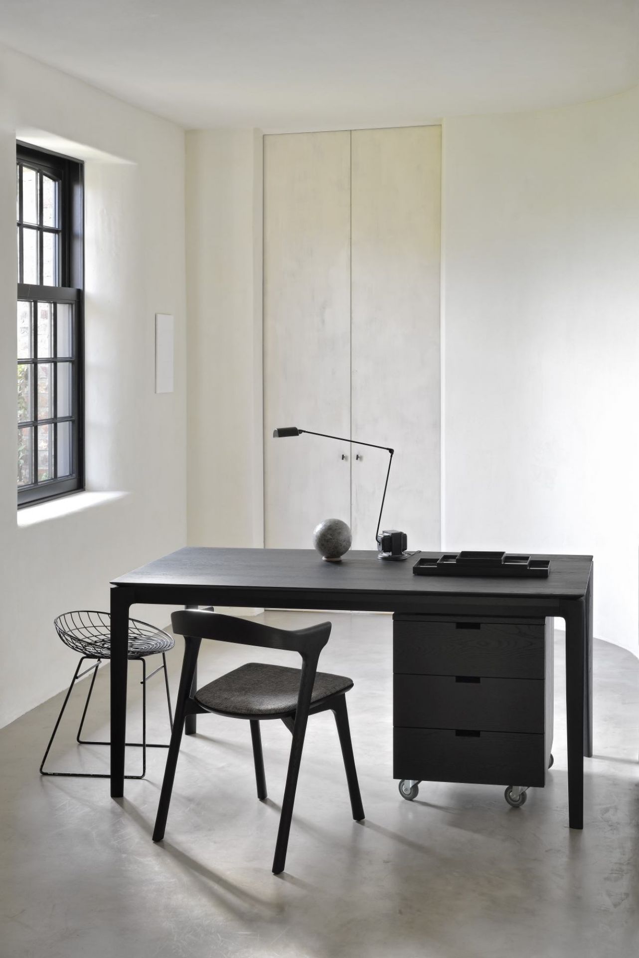 Schwarzer Bok Eiche Tisch von Ethnicraft mit Stuhl und Rollcontainer in einem hellen Raum.