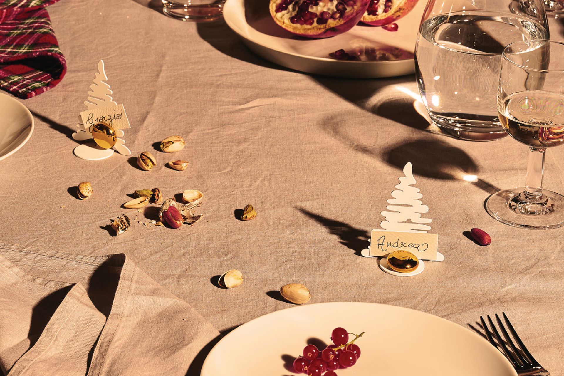 Weißer Barkplace Tree Tischkartenhalter als Weihnachtsdeko auf gedecktem Tisch mit Namen, Geschirr und Nüssen.