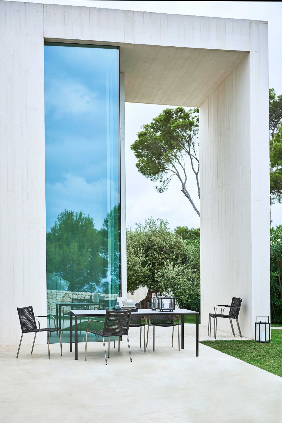 Cane-Line Straw Armlehnstuhl für den Garten: Schwarzer Outdoor Stuhl mit Armlehnen am Esstisch.