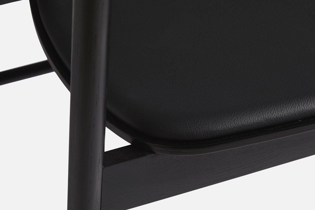 Detailaufnahme: Schwarzer Soma Dining Chair Stuhl von Woud mit gepolstertem Sitz.