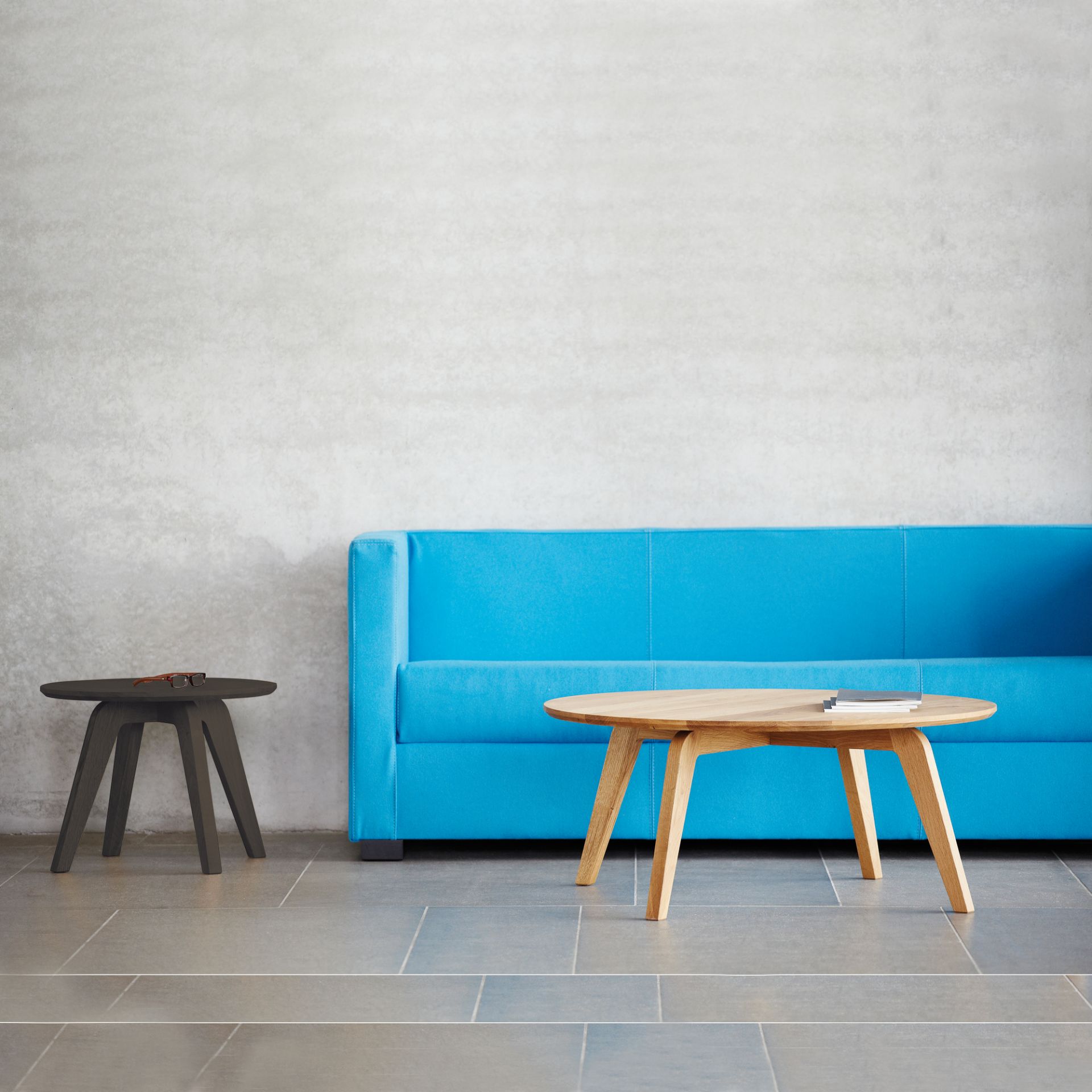 Dweller Couchtisch Natur von Jan Kurtz, runder Holztisch vor blauem Sofa.