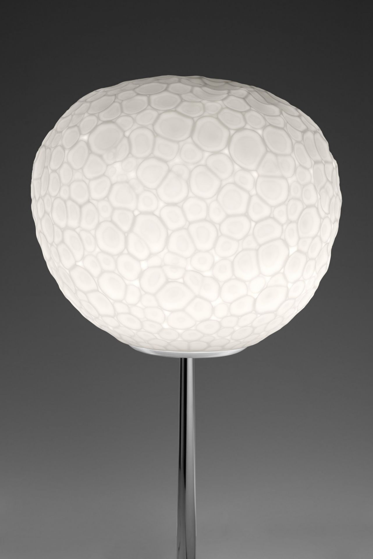 Meteorite Tischleuchte von Artemide: Runde, weiße Designerlampe mit Struktur auf einem schlanken, silbernen Fuß.