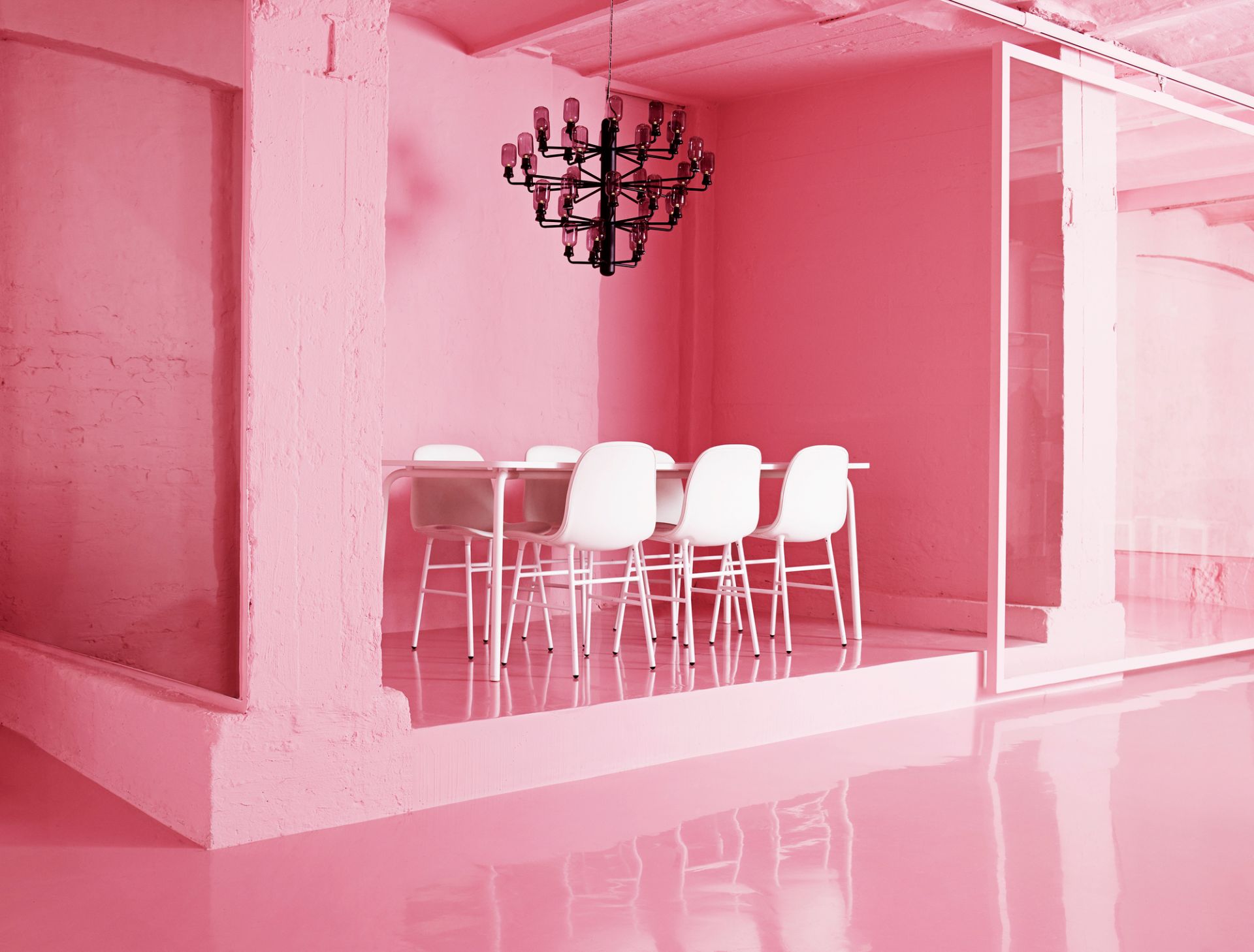 Amp Chandelier Pendelleuchte in Gold und Grün über Esstisch in einem pinken Raum.