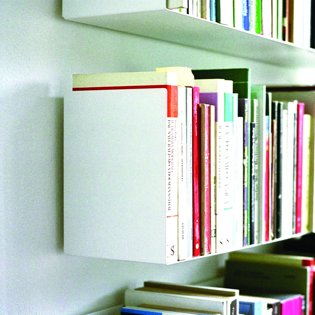 Weißes Wandregal a Linea1 von Müller Möbelwerkstätten mit Büchern, modernes Bücherregal für Wohnzimmer und Büro.