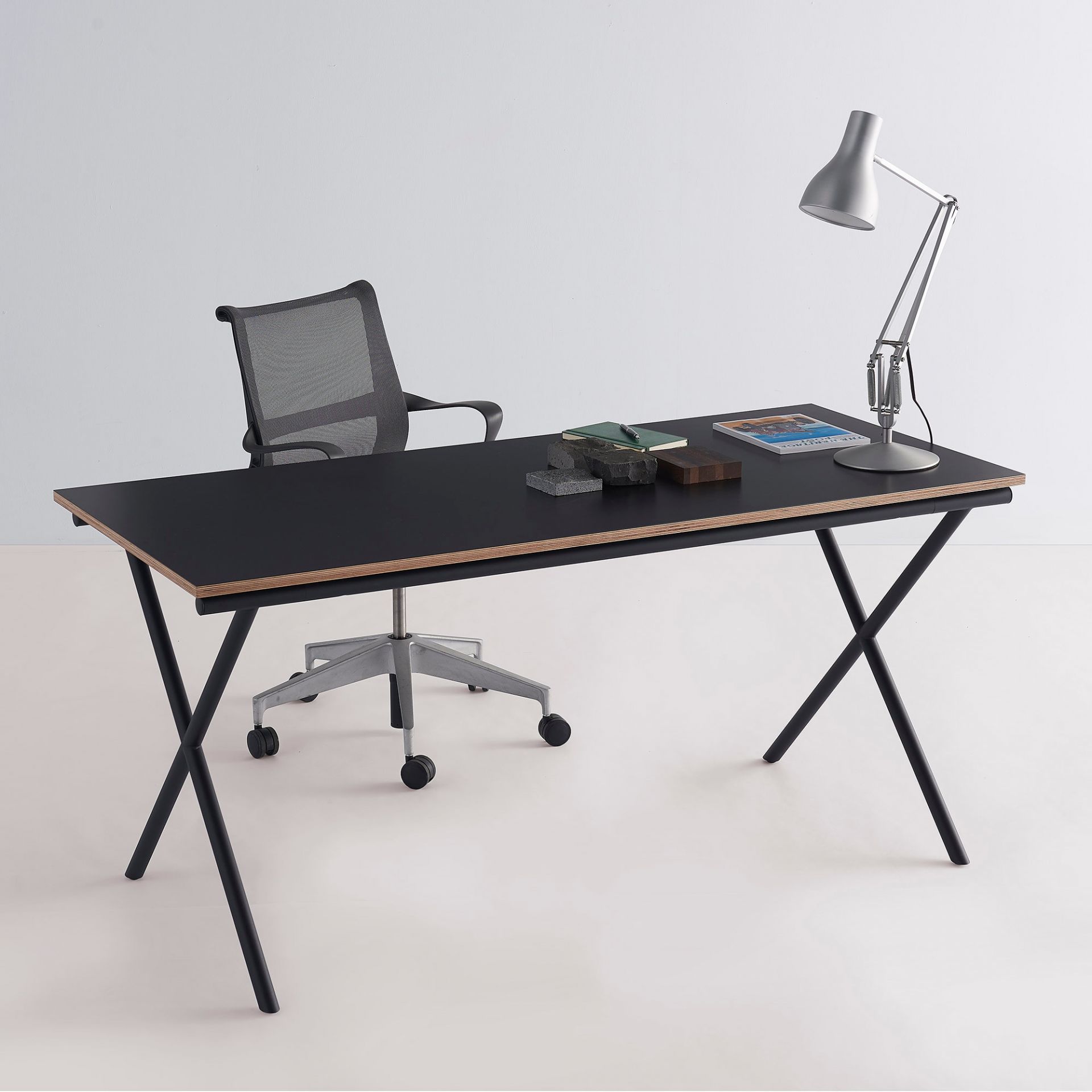 Schwarzer Ito Arbeitstisch mit X-förmigem Gestell, Bürostuhl und Lampe. Moderner Schreibtisch für Büro und Homeoffice.
