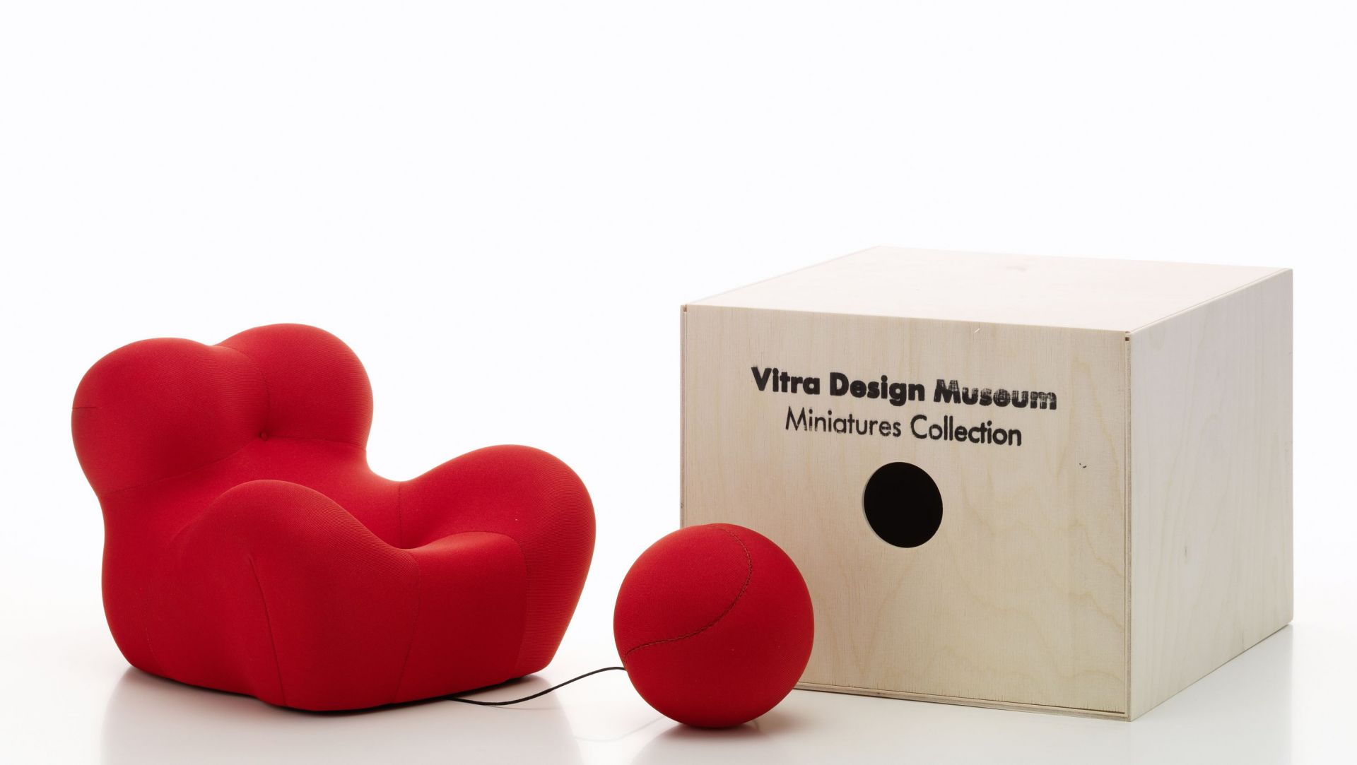 Roter La Mamma Sessel Miniatur von Vitra mit passendem Hocker und Holzkiste.