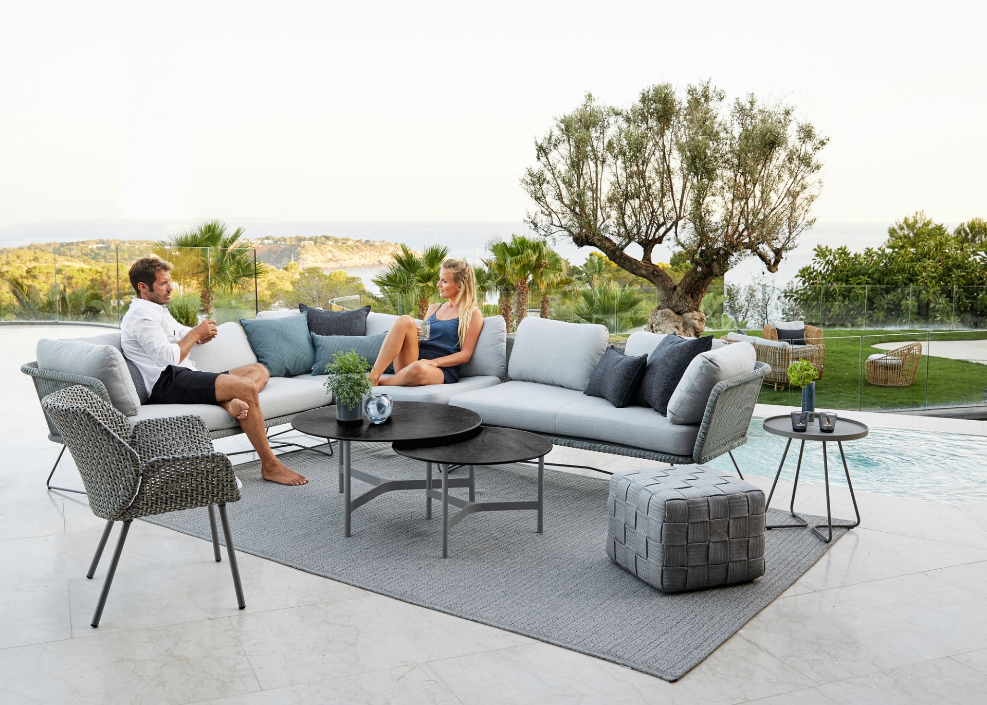 Horizon Outdoor Modulsofa von Cane-Line: Graues Lounge-Sofa mit Personen auf einer Terrasse.