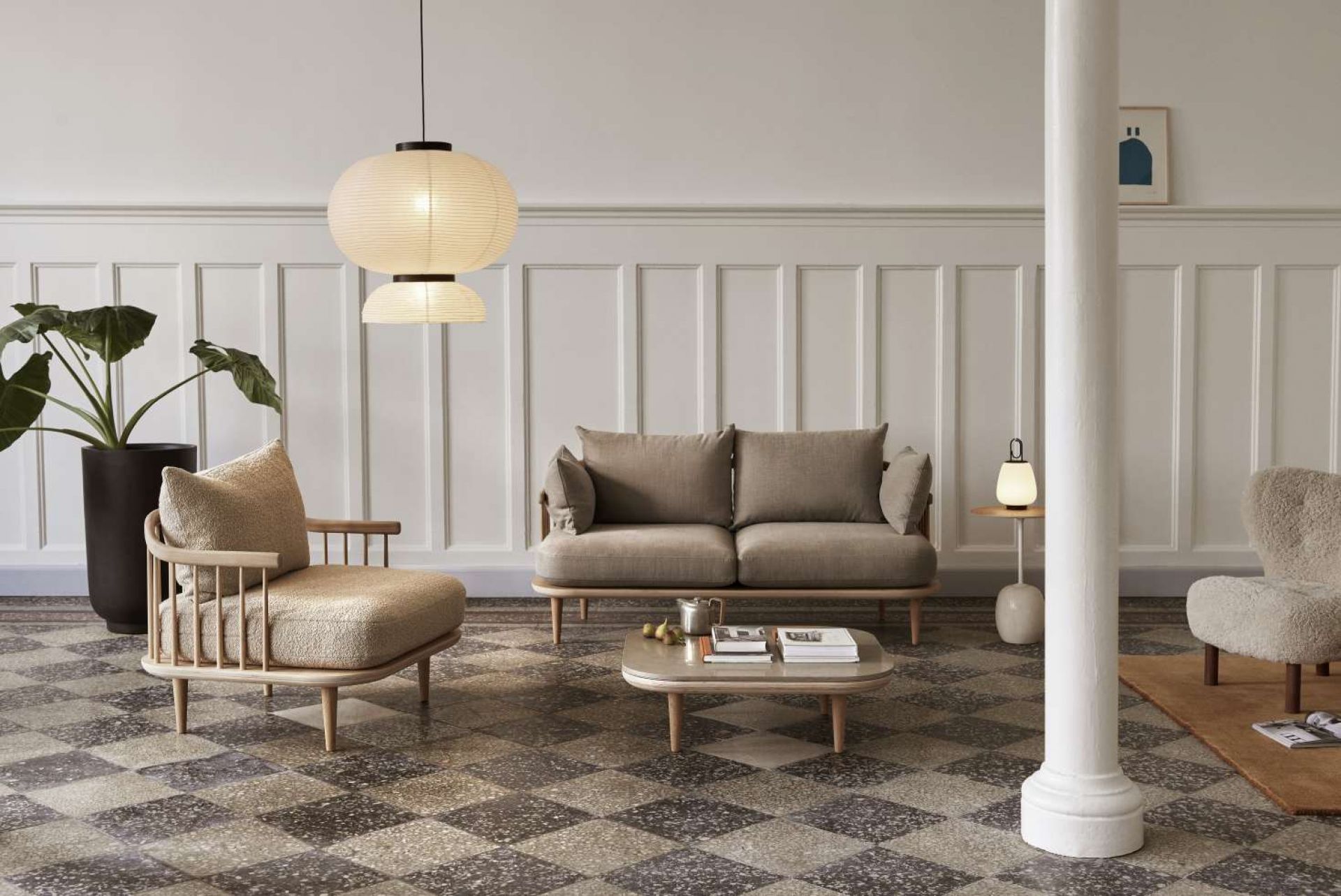 Wohnzimmer mit AndTradition Fly Couchtisch, Sofa und Sessel in Beige- und Naturtönen.