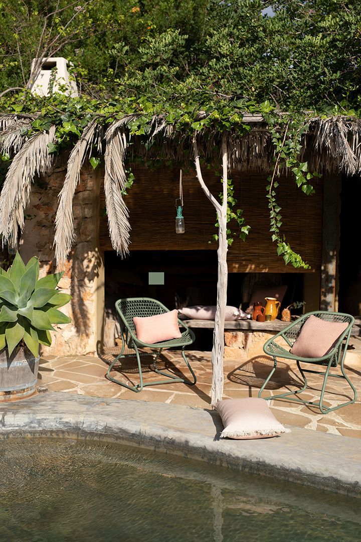 Zwei grüne Fermob Sixties Sessel mit Kissen im Außenbereich unter einem schattigen Dach.