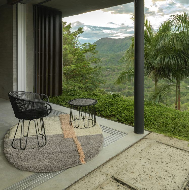 Schwarzer Circo Dining Chair Outdoor Stuhl mit Tisch auf Terrasse vor grüner Landschaft.